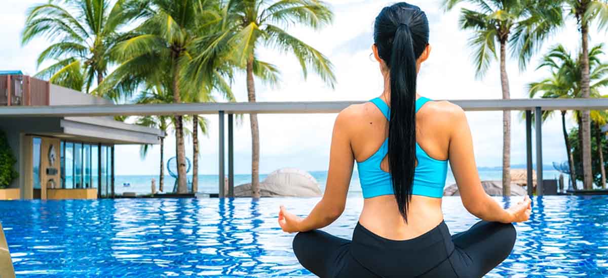 A woman doing Yoga in front of swimming pool