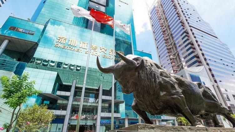 Statue of bull in front of Shenzen stock exchange glass building