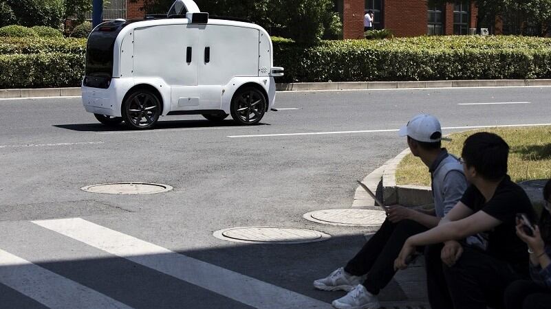 People looking at an autonomous vehicle out for a test drive in China