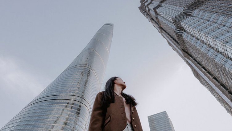 A girl standing and looking at high rise building
