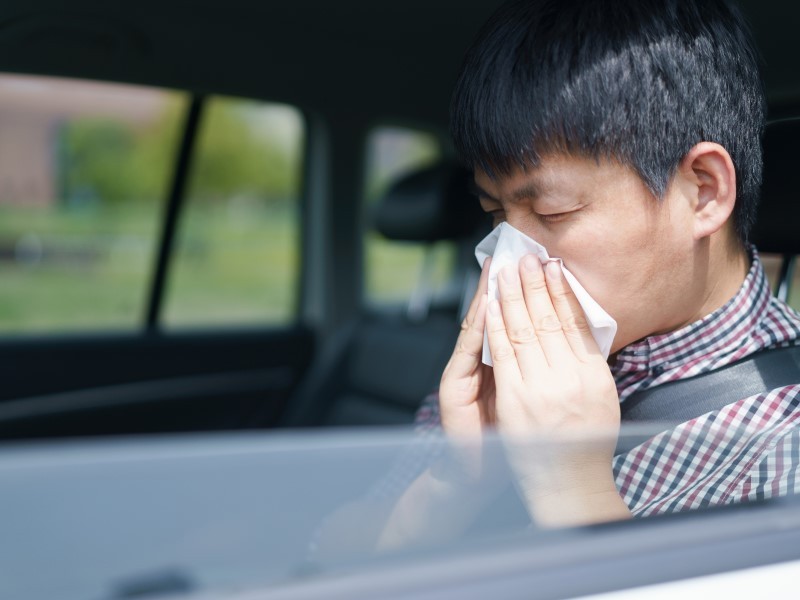 Man sneezing in a car