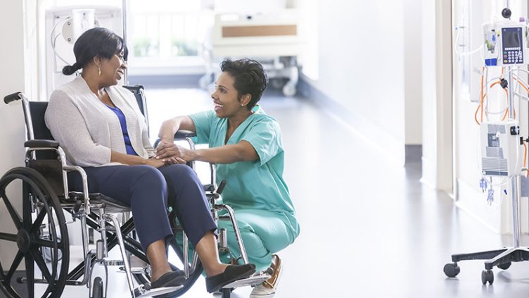 Patient on wheelchair and nurse happily interacting in the hospital