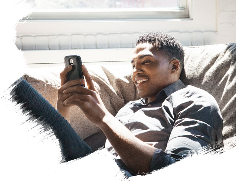 Happy Man sitting on sofa and looking at messages on phone